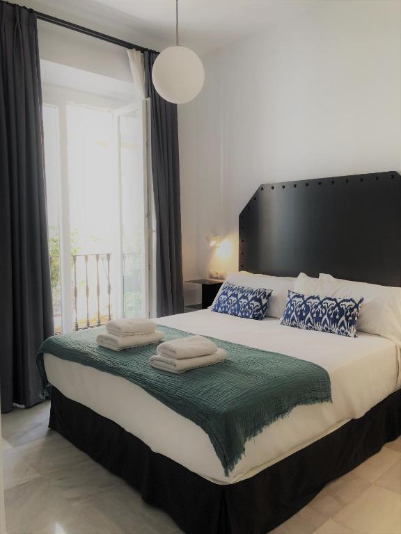 a bedroom with a large bed with two towels on it at Hostal Hom Museo in Seville