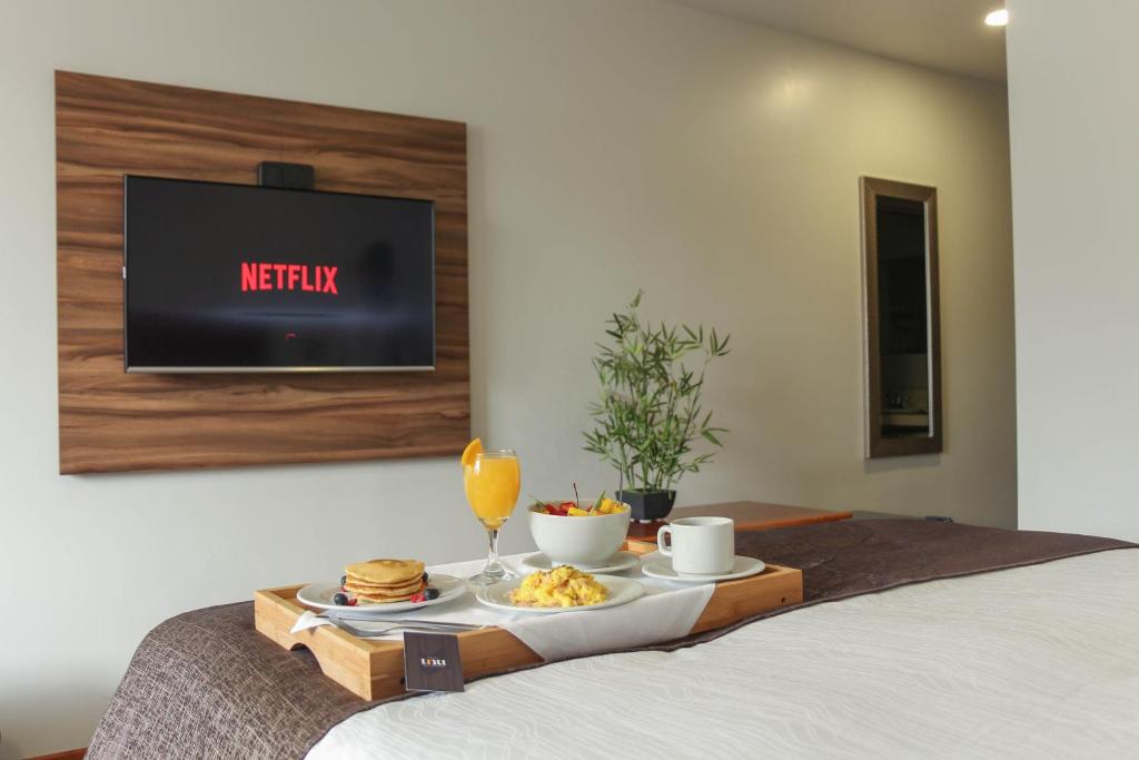 a tray of food on a bed with a tv at Hotel Unu in Huancayo