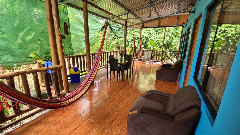 ein Wohnzimmer mit einer Hängematte auf einer Veranda in der Unterkunft El Manantial de Corcovado in Dos Brazos