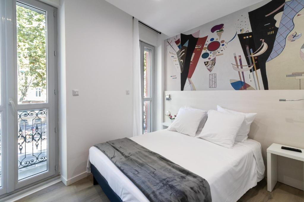 a bedroom with a white bed and a window at Residence le Pastel Jeanne d'Arc in Toulouse