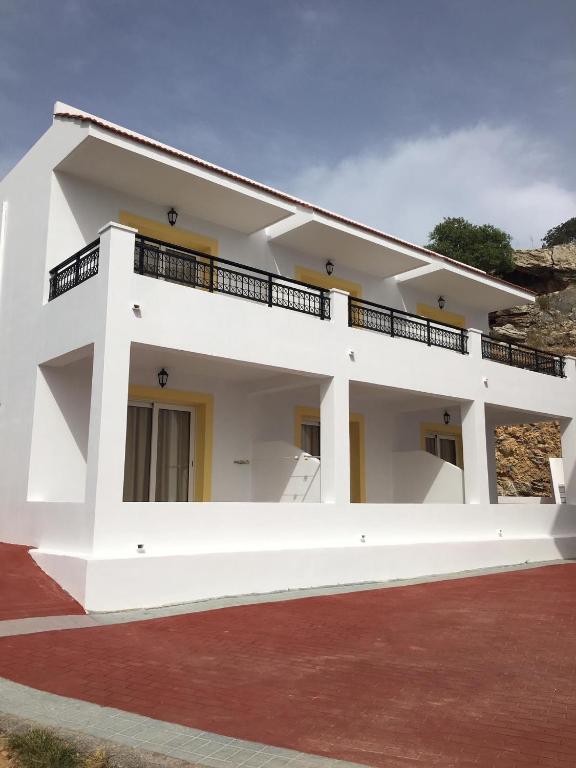 a large white house with a red brick driveway at Coloma Apartments Pefkos in Pefki