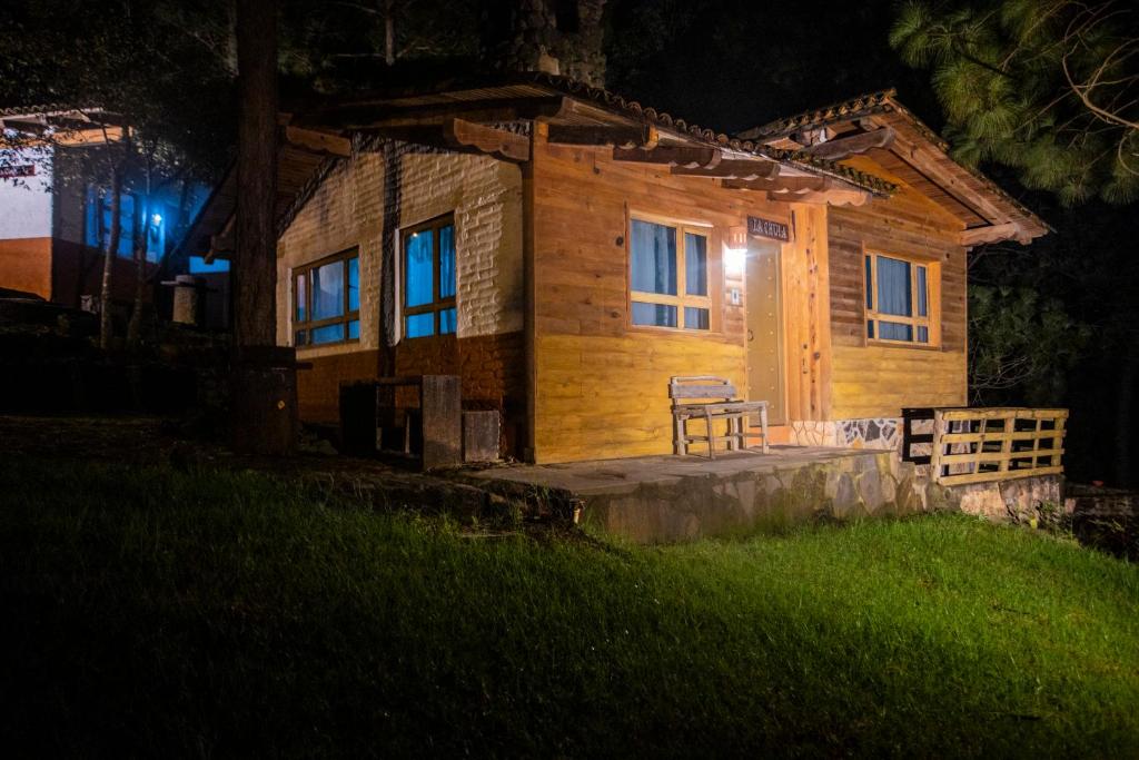 una cabaña de madera por la noche con un banco delante en Cabañas RuizSeñor en Mazamitla