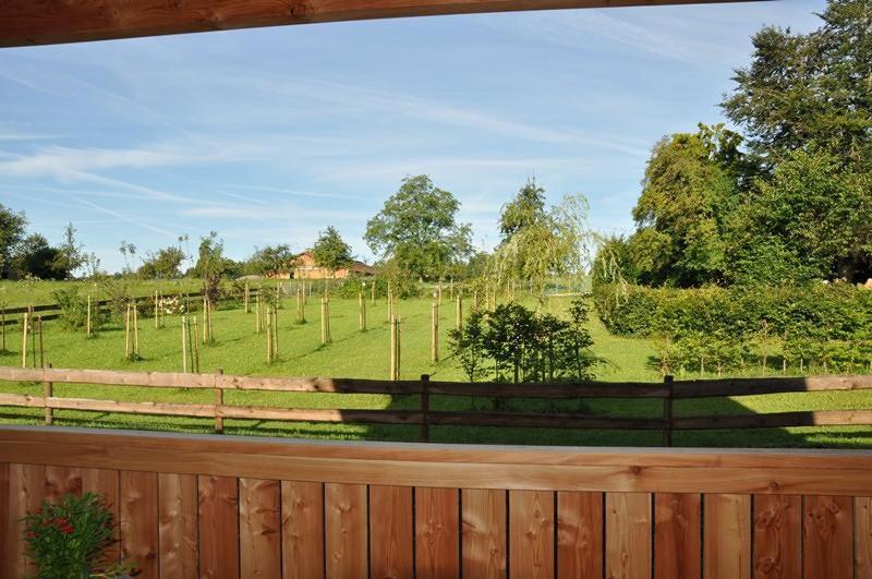 una valla con vistas a un campo con árboles en Ferienwohnung Bauer Katrin und Florian en Prien am Chiemsee