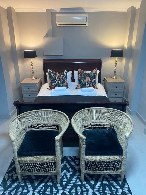 a bedroom with two wicker chairs and a bed at Rest at Lieben in Bloemfontein