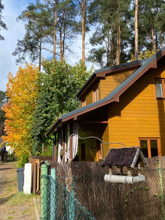 une maison jaune avec une clôture devant elle dans l'établissement Lawendula domek nad Miedwiem, à Morzyczyn