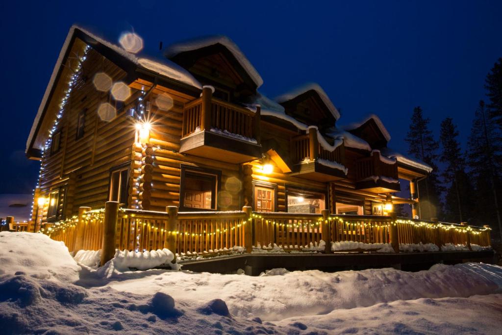 Cabaña de madera decorada con luces de Navidad en la nieve en Castle Mountain Chalets, en Castle Junction