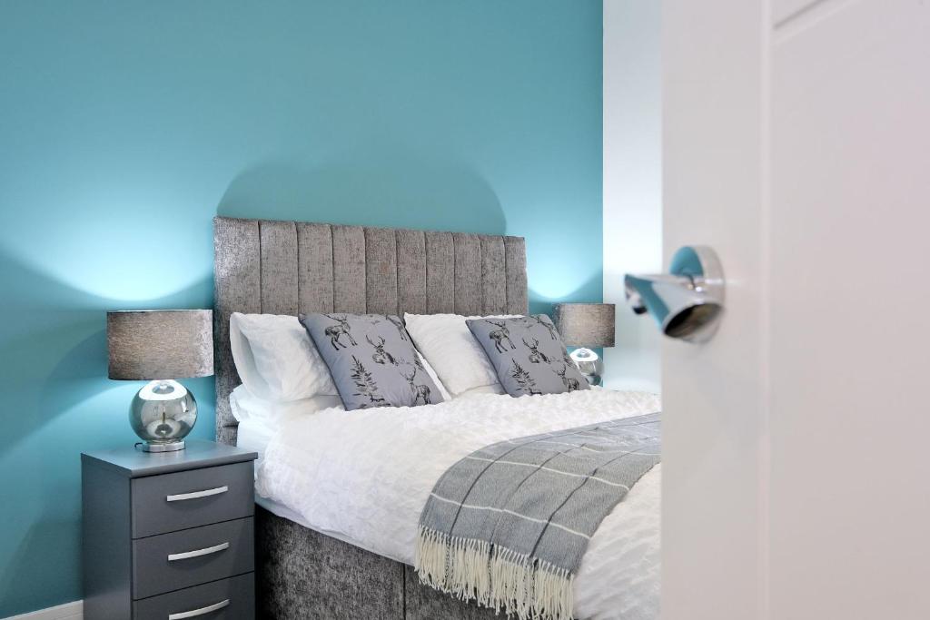 a bedroom with a bed and a blue wall at 5* Luxury 1 Bedroom Apartment in City Centre in Aberdeen