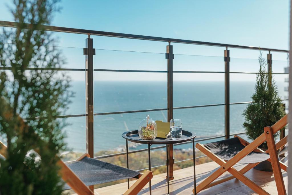 een tafel en stoelen op een balkon met uitzicht op de oceaan bij Sea & Sky apartments in Odessa