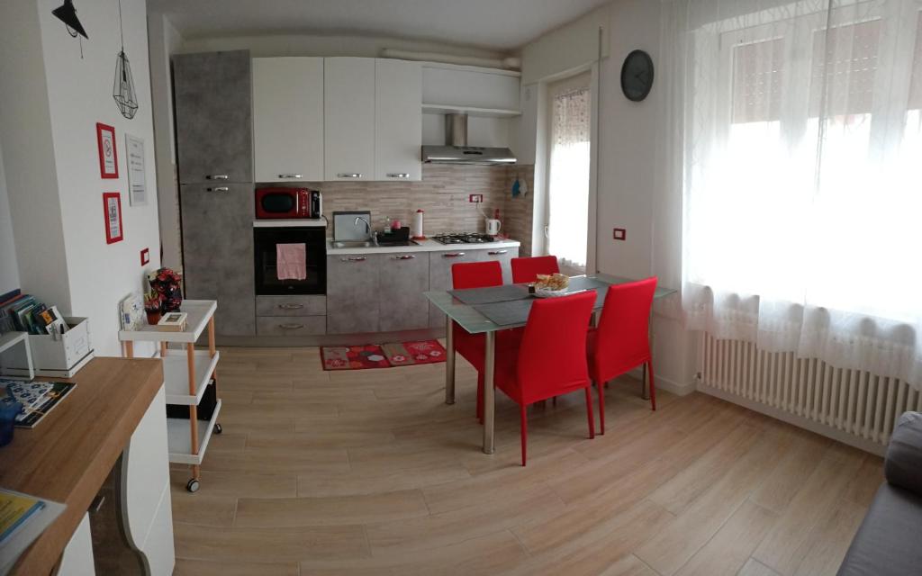 Il dispose d'une cuisine et d'un salon avec une table et des chaises rouges. dans l'établissement Rio Taglio, à Cervignano del Friuli