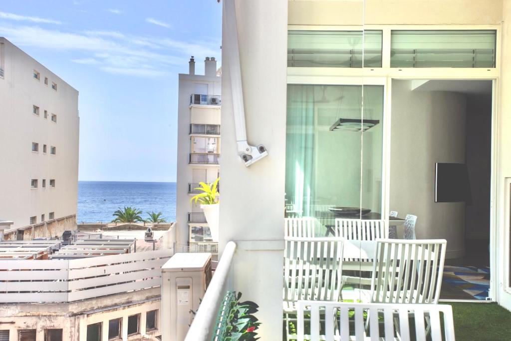 a balcony with white chairs and a view of the ocean at Luxurious 2 Bedrooms Apartment, 30 meter from beach in Nice