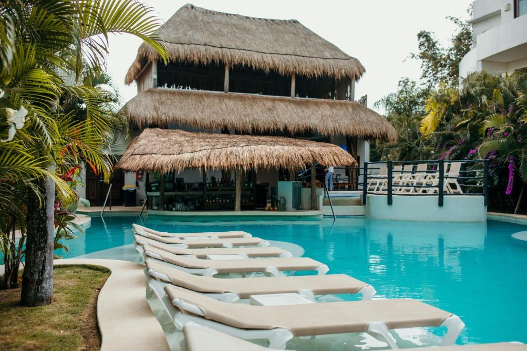 a group of chaise lounge chairs in a swimming pool at Mak Nuk Village - Clothing Optional in Tulum