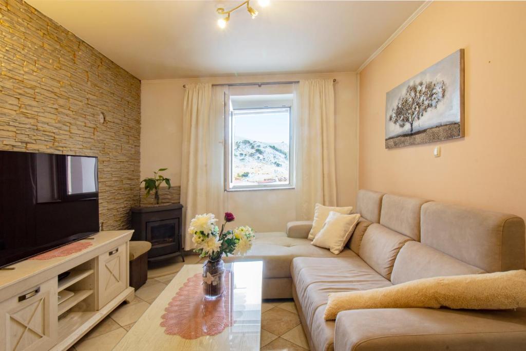 a living room with a couch and a tv at Toncica Sunny terrace with seaview and shaded BBQ area in Metajna