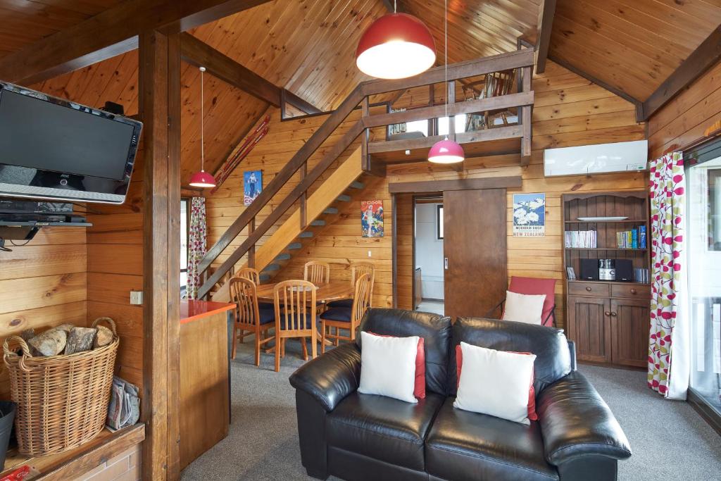 a living room with a leather couch and a tv at Retro Inn 2 - Lake Tekapo in Lake Tekapo