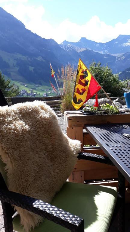 un ours en peluche assis sur une chaise à une table avec drapeau dans l'établissement Chalet Gotthelf Gartenstudio, Ferien mit Hund, à Adelboden