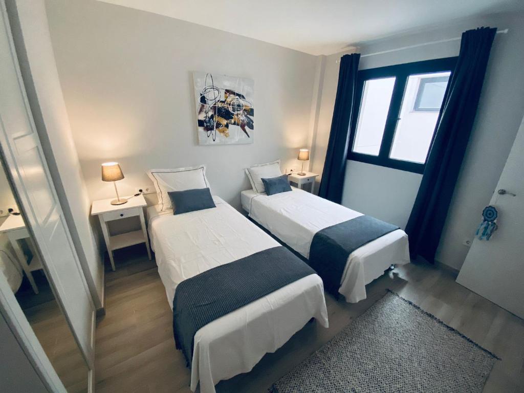 two beds in a small room with a window at Apartamento de obra nueva cerca de la playa by Top Stay in El Médano