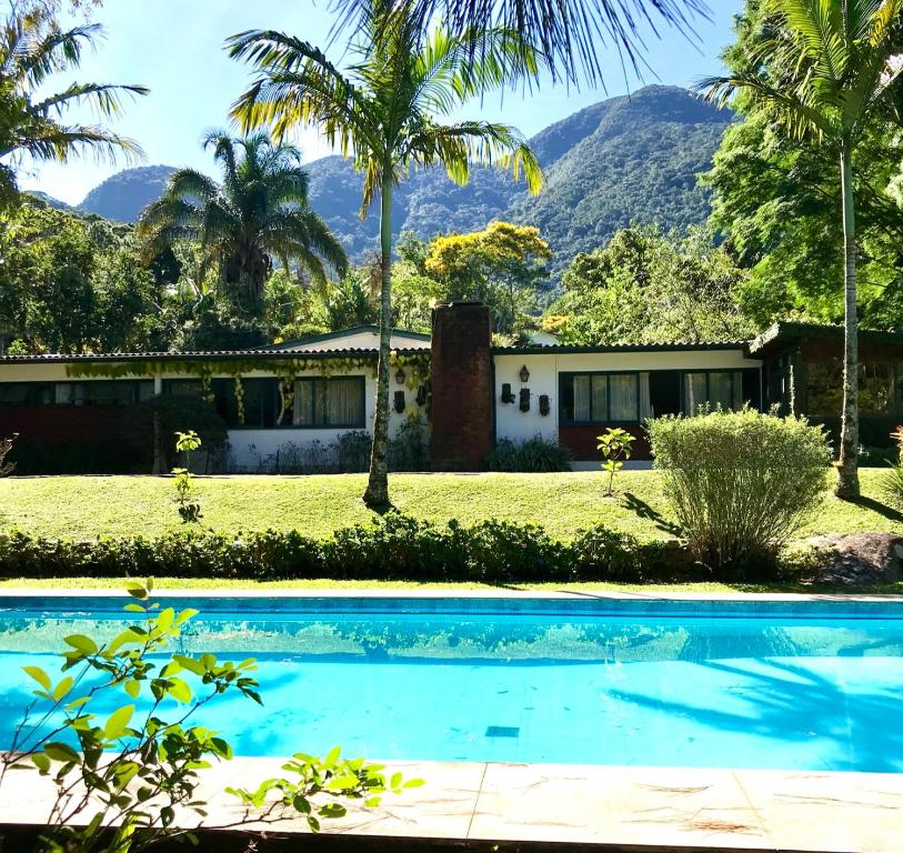 une maison avec une piscine et des montagnes en arrière-plan dans l'établissement Pinheiros do Rocio, à Petrópolis