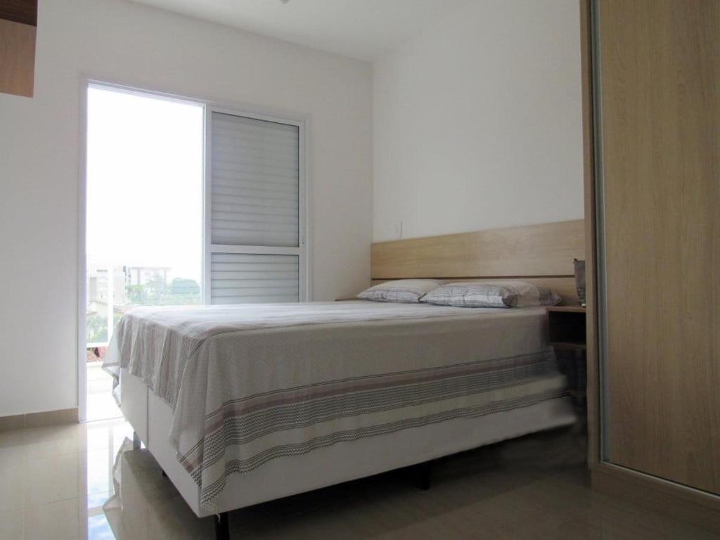 Un dormitorio con una cama y una ventana grande en Apartamento completo p temporada Ubatuba, excelente localização com conforto e economia, en Ubatuba