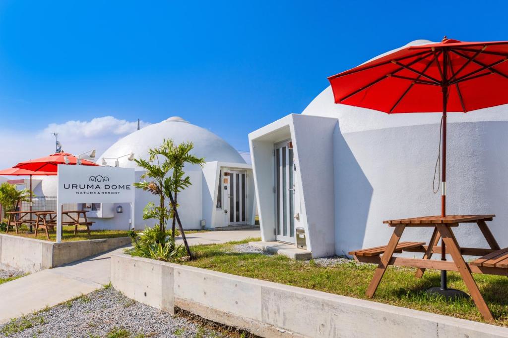 einen Tisch mit einem roten Regenschirm neben einem Gebäude in der Unterkunft Uruma Dome Okinawa in Uruma
