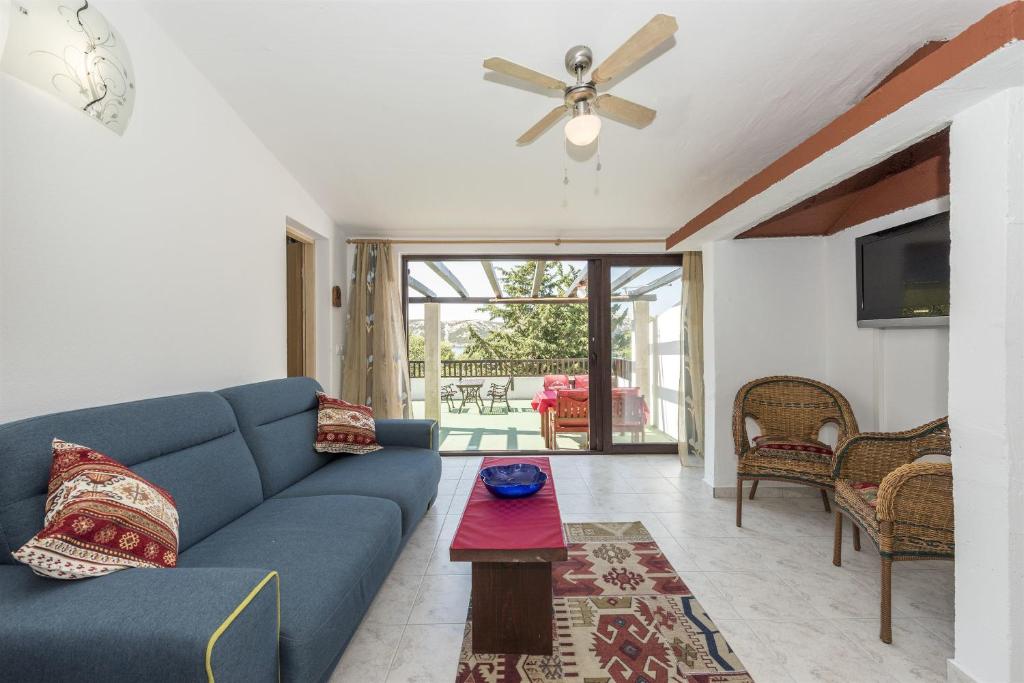 salon z niebieską kanapą i wentylatorem sufitowym w obiekcie Bungalow Small House w mieście Stara Novalja