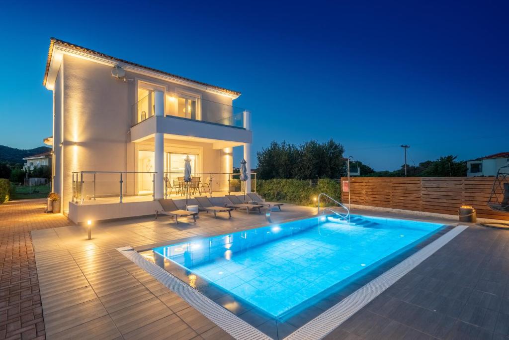 a villa with a swimming pool in front of a house at Artemon New Luxury Villa in Skala Kefalonias