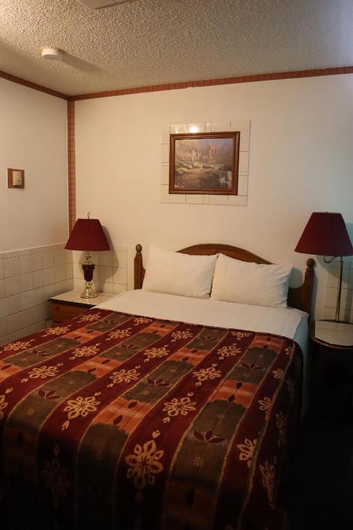 a bedroom with a large bed and two lamps at Vista Motel in Vegreville