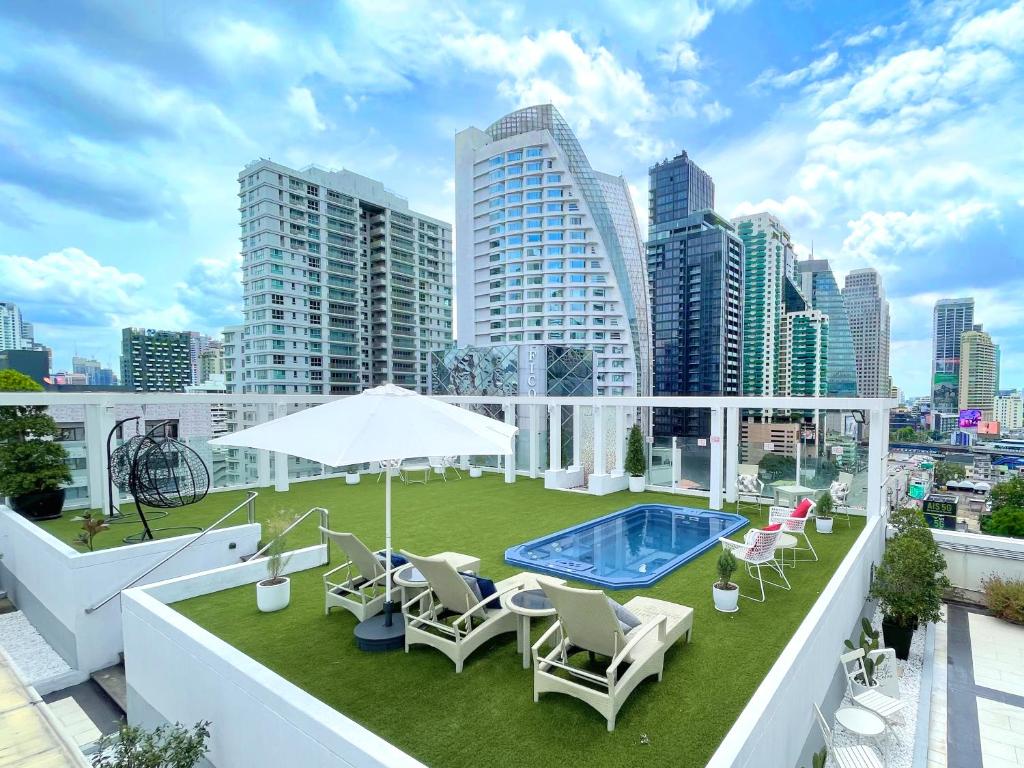 a rooftop patio with chairs and a swimming pool on a building at FuramaXclusive Asoke, Bangkok in Bangkok