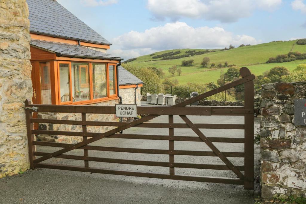 a wooden gate to a house with a sign on it at Pendre Uchaf in Derwen
