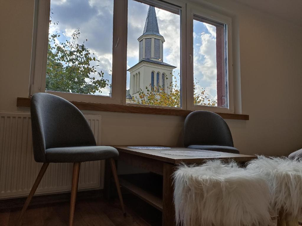 een kamer met 2 stoelen, een tafel en een raam bij Apartament Nad lipami in Hajnówka