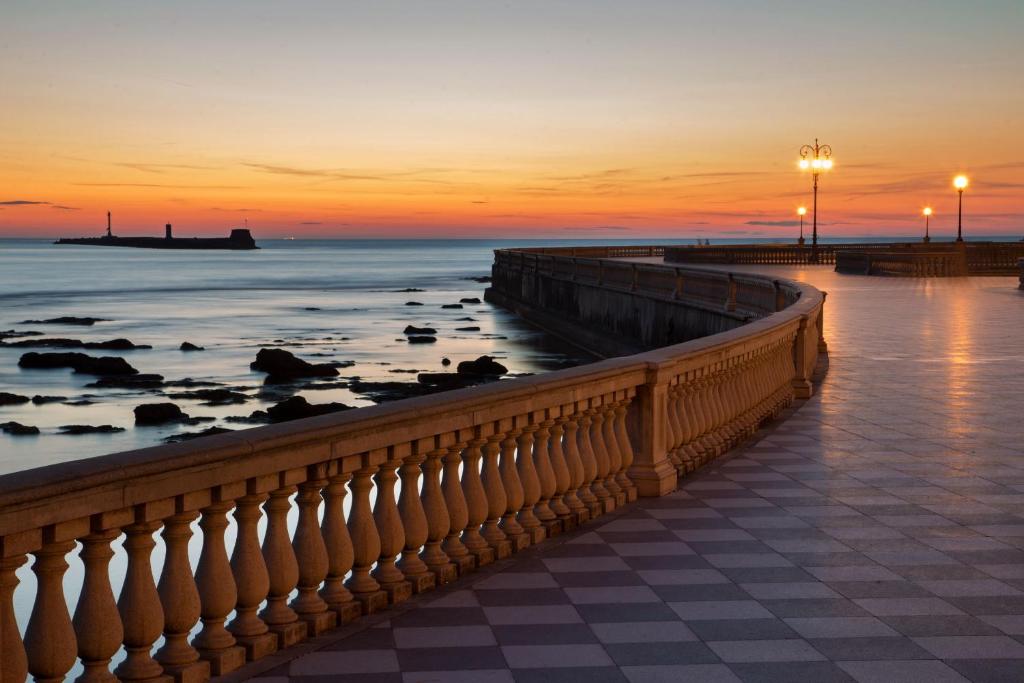 a sunset over the ocean and a pier at Hotel Mediterraneo in Livorno