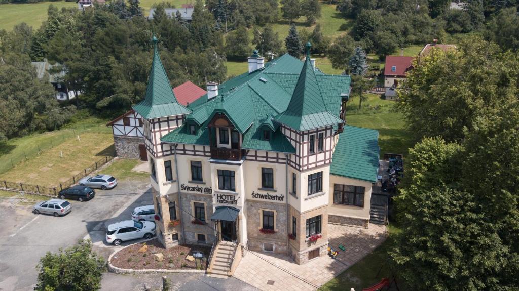 eine Luftansicht eines großen Hauses mit grünem Dach in der Unterkunft Hotel Švýcarský dům in Sněžnik