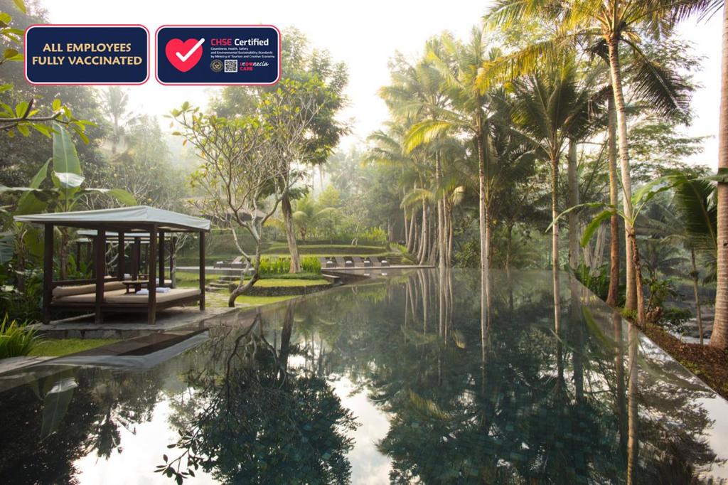 a swimming pool in a park with palm trees at Kayumanis Ubud Private Villas & Spa in Ubud