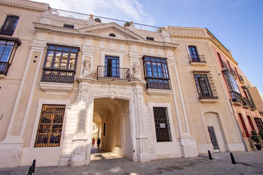 een groot gebouw met een boog ervoor bij Real Casa de la Moneda Deluxe Apartments in Sevilla