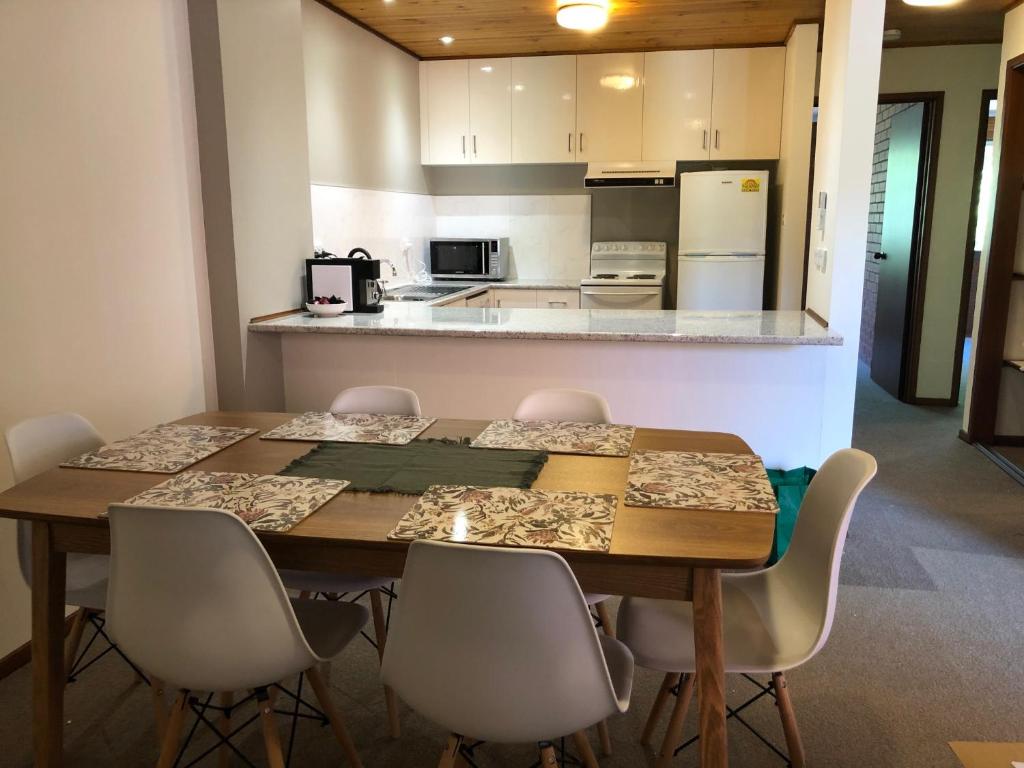 a dining room table with chairs and a kitchen at Kingston Pines in Kingston 