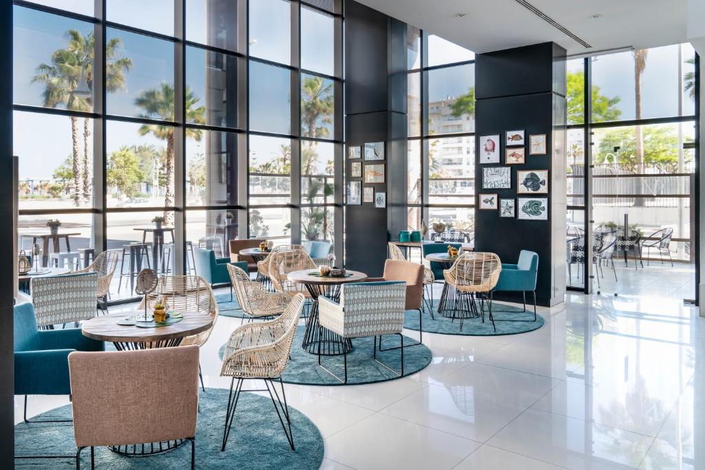 a lobby with tables and chairs and windows at Vincci Málaga in Málaga