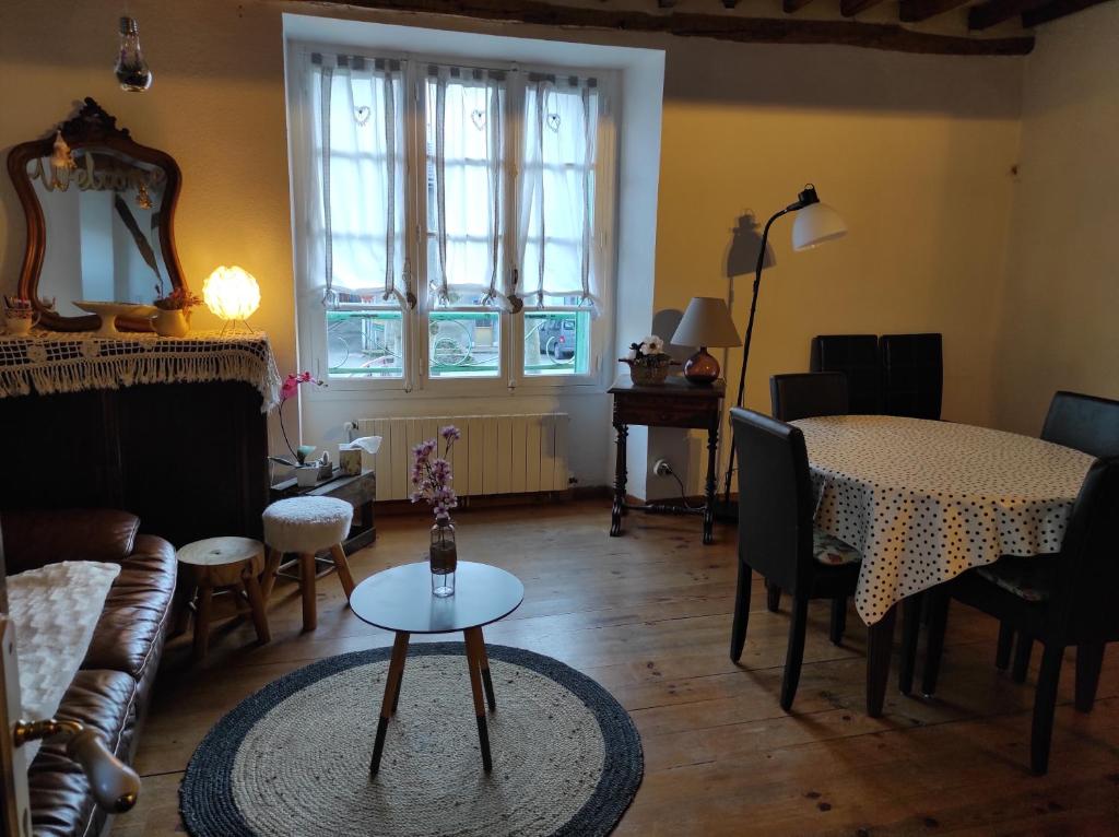 a living room with a table and a dining room at La maison des vacances in Auzat