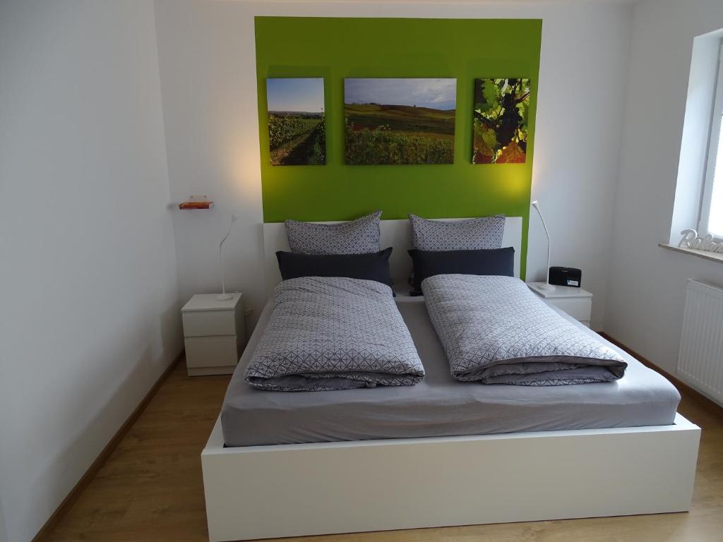a bedroom with a bed with a green wall at Rheinhessen Apartment in Nieder-Olm