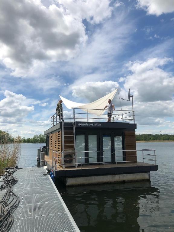 a man standing on top of a boat on the water at Schwimmende Ferienwohnung, Hausboot Urlaub als Festlieger am Steg in Zehdenick
