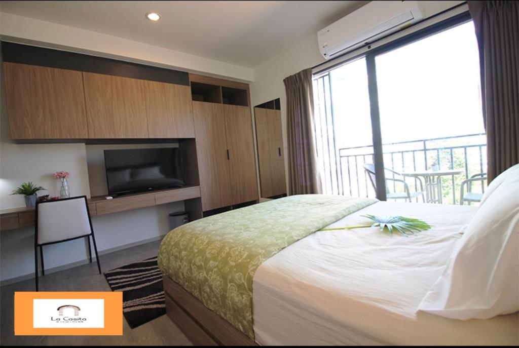 a bedroom with a bed and a tv and a balcony at Rose 'Lacasita Huahin in Hua Hin