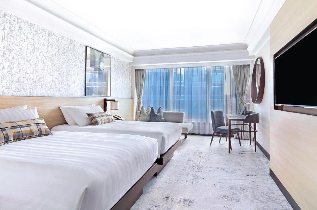 ein Hotelzimmer mit 2 Betten und einem Flachbild-TV in der Unterkunft Harbour Grand Kowloon in Hongkong
