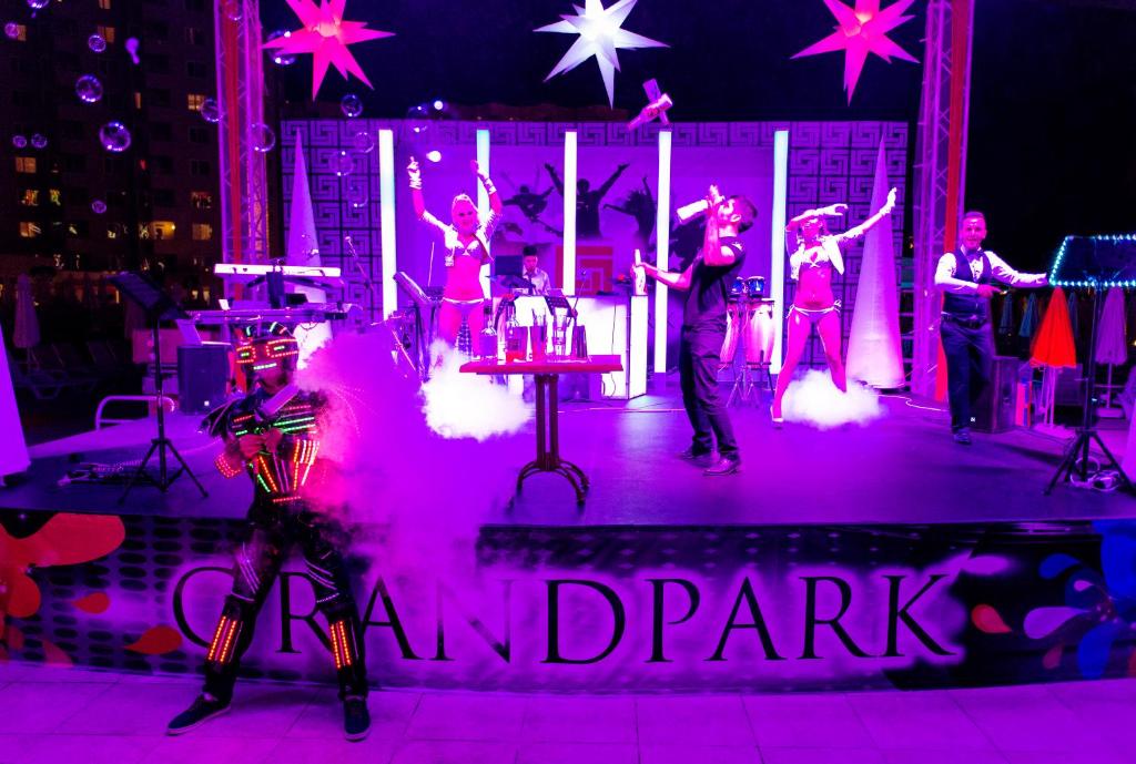 a group of people on a stage with pink lights at Grand Park Lara Hotel in Lara
