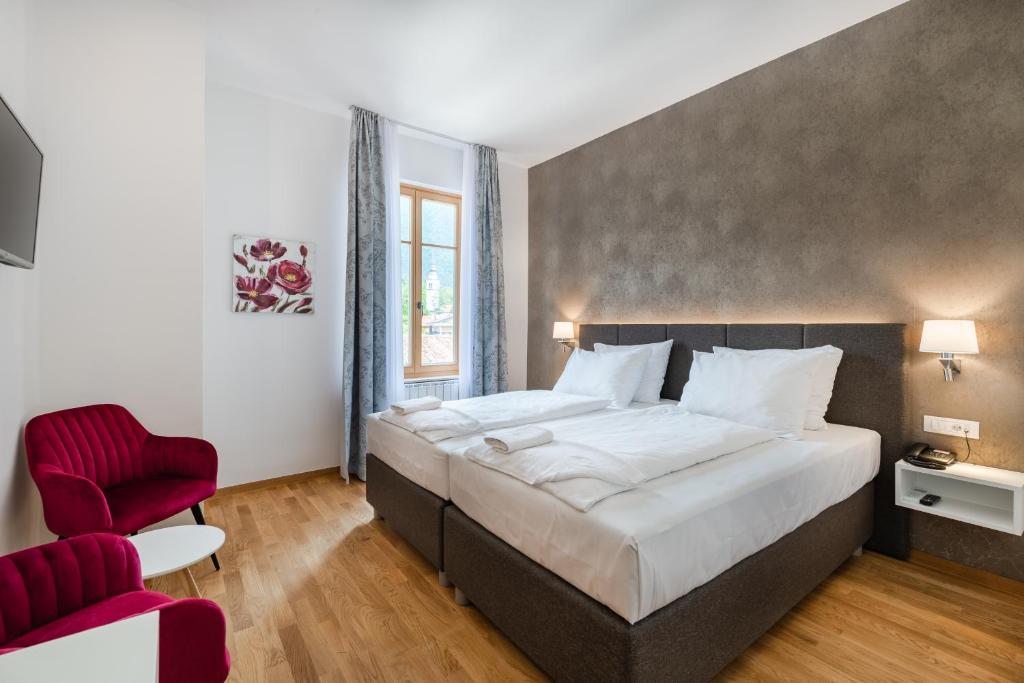 a bedroom with a large bed and a red chair at Hotel Dvorec in Tolmin