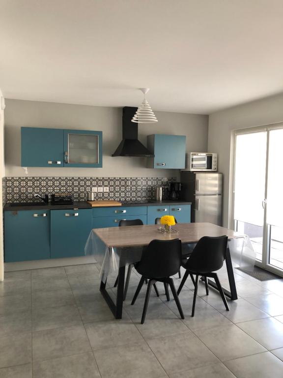 une cuisine avec des armoires bleues et une table et des chaises dans l'établissement Gerardmer : Residence 