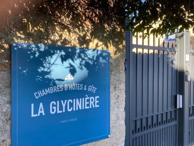 een bord op een hek naast een hek bij La Glycinière Chambres d'Hôtes in Pont-Croix