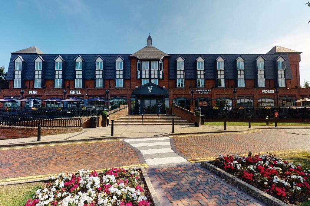 a large brick building with flowers in front of it at Village Hotel Nottingham in Nottingham