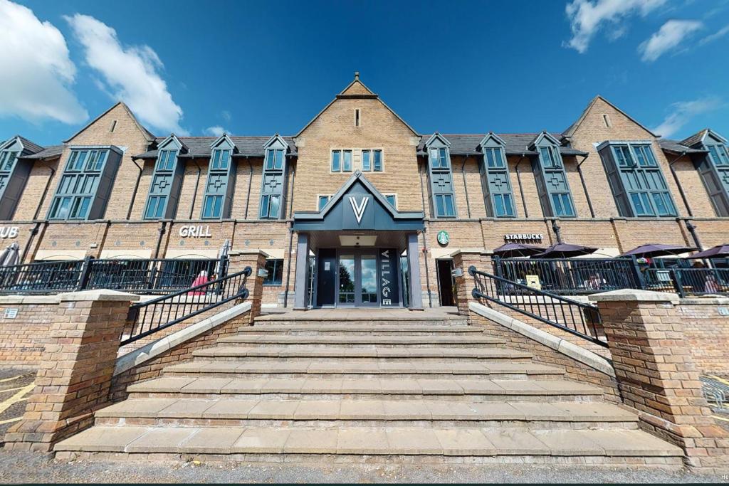 a large brick building with stairs leading to the entrance at Village Hotel Leeds North in Leeds