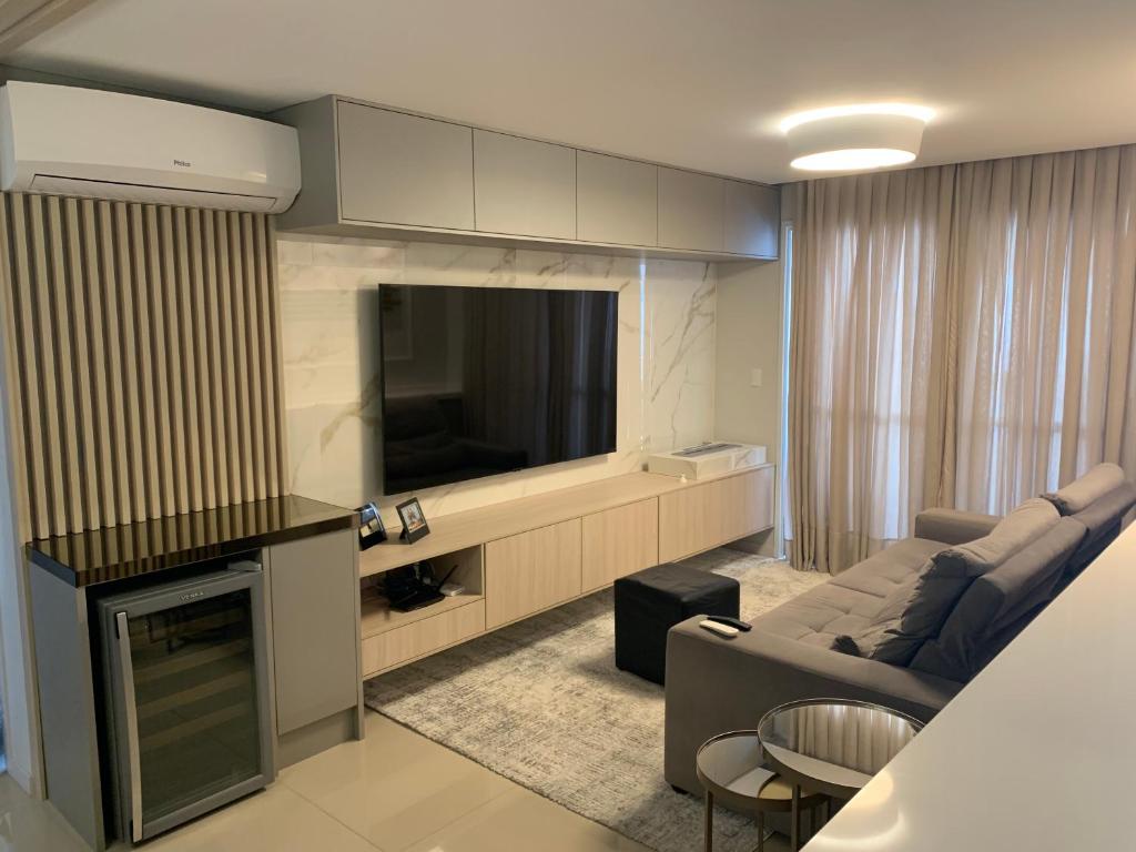 uma sala de estar com um sofá e uma televisão e uma sala de estar em Condominio dunas do Leste 2 em Florianópolis