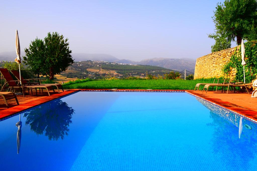 una gran piscina azul con sillas y árboles en Villa Casa Alta, en Ronda