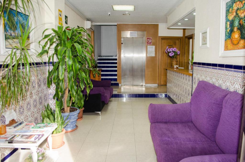 um átrio hospitalar com mobiliário e plantas roxas em Pensión Pardo em Benidorm