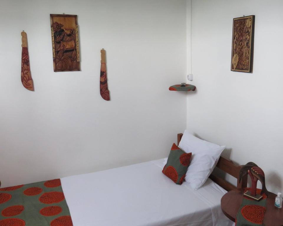 a white bedroom with a bed and some pictures on the wall at Micaval Residential in São Tomé