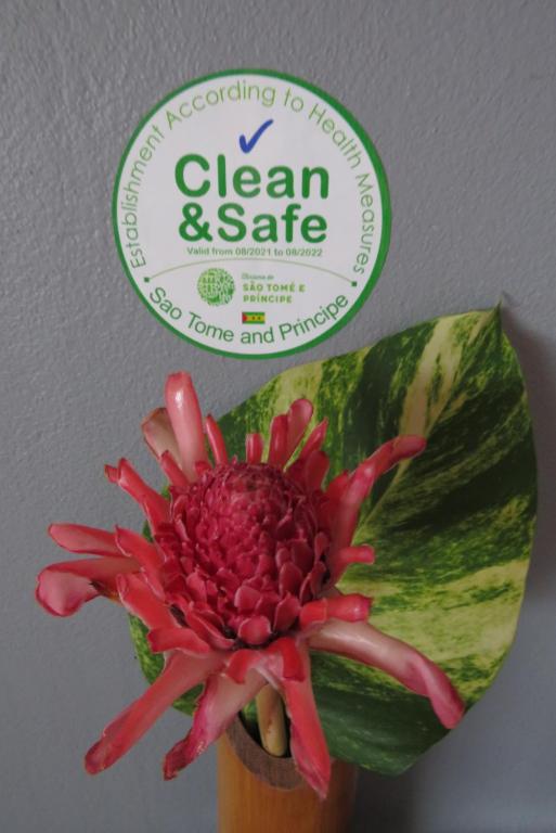 a bottle of clean and safe next to a flower at Micaval Residential in São Tomé